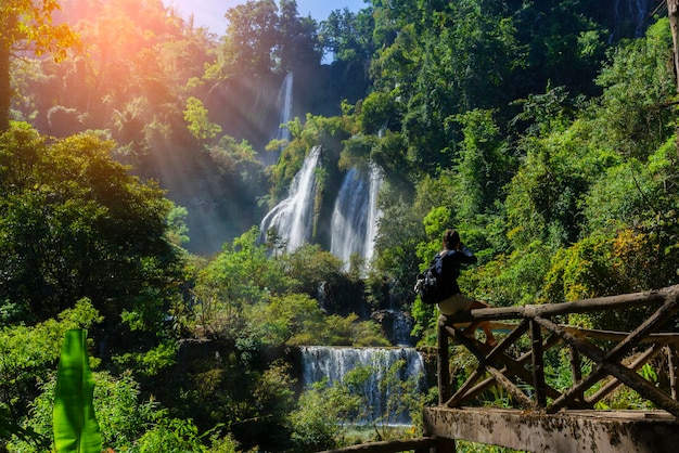 Femme asiatique prenant des photos de la cascade Thi Lo Su ou Thee Lor Sue située dans la réserve faunique d'Umphang, site du patrimoine mondial de l'UNESCO, province de Tak, Thaïlande