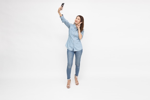 Femme asiatique prenant un selfie par téléphone portable isolé sur fond blanc