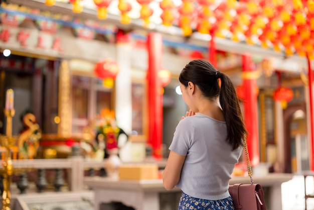 Une femme asiatique prie dans un temple chinois