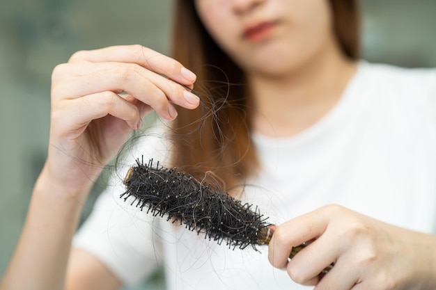 Une femme asiatique a un problème de perte de cheveux longs attachée à une brosse à peigne