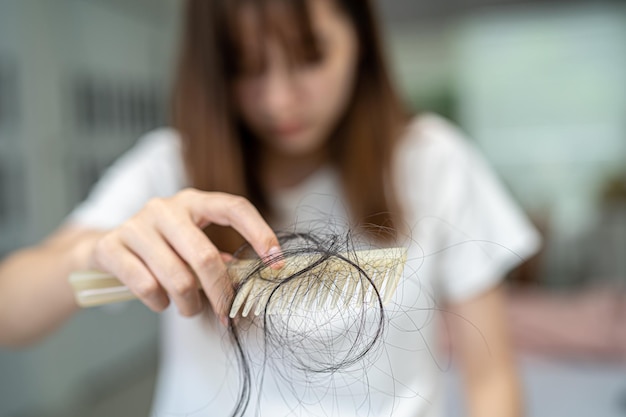 Une femme asiatique a un problème de perte de cheveux longs attachée à une brosse à peigne