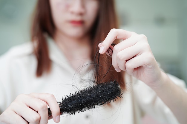 Une femme asiatique a un problème de perte de cheveux longs attachée à une brosse à peigne