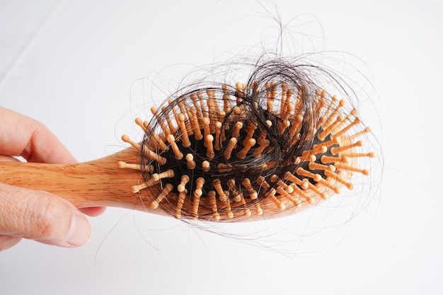 Une femme asiatique a un problème de perte de cheveux longs attachée à une brosse à peigne