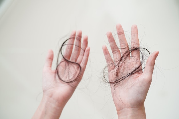 Une femme asiatique a un problème avec la perte de cheveux longs attachée dans sa main