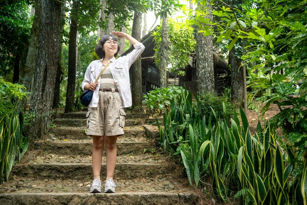 Une femme asiatique qui regarde dans la forêt.