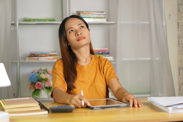 Une femme asiatique qui travaille à domicile, fatiguée des papiers qui ne sont pas remplis à temps.