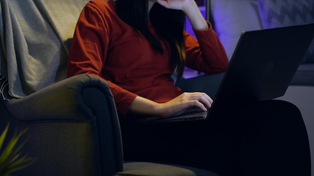 Femme asiatique regardant un film sur un ordinateur portable la nuit à la maison. Mode de vie relaxant et récréatif.