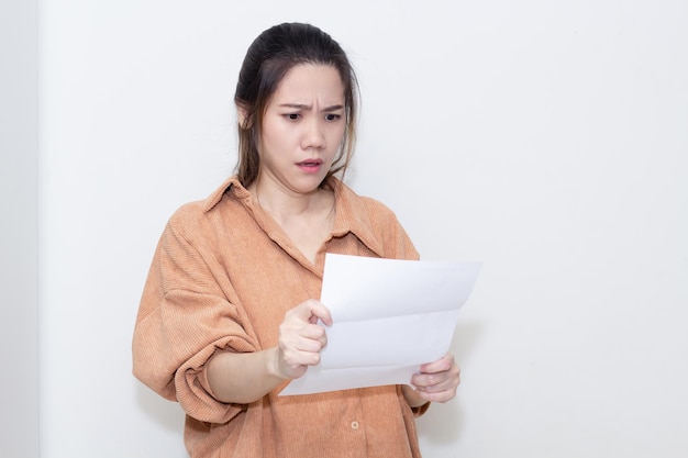 Une femme asiatique regarde une facture ou une facture qu'elle est en retard et énorme de dette avec un visage inquiet et choqué. Pas d'argent pour payer.