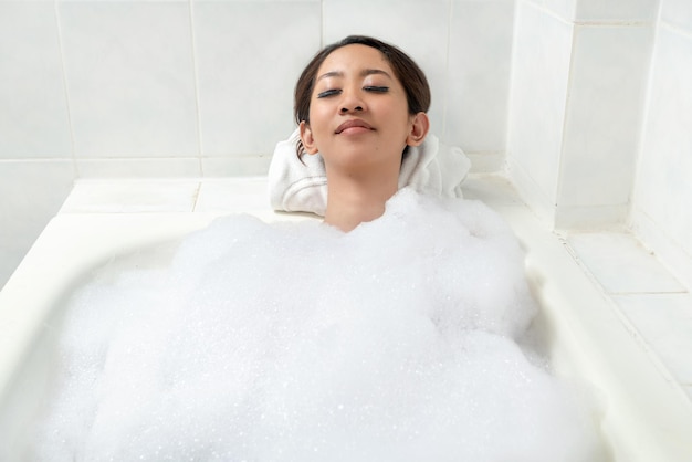 Femme asiatique relaxante sur la baignoire