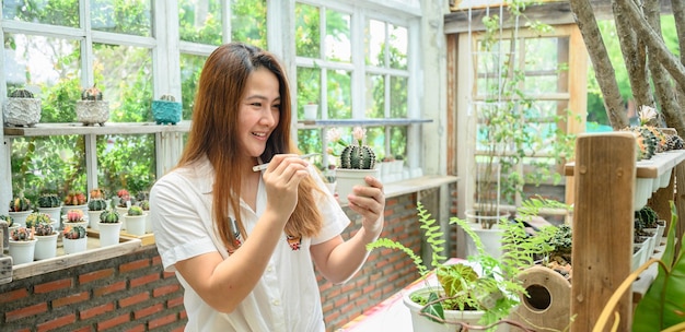 Femme asiatique relaxante avec cactus dans le jardin. Mode de vie de jardinage à la maison pendant les vacances d'été.