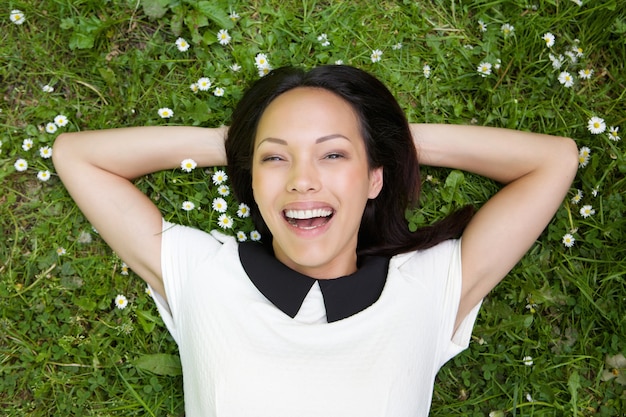 Femme asiatique relaxante sur l&#39;herbe et souriant