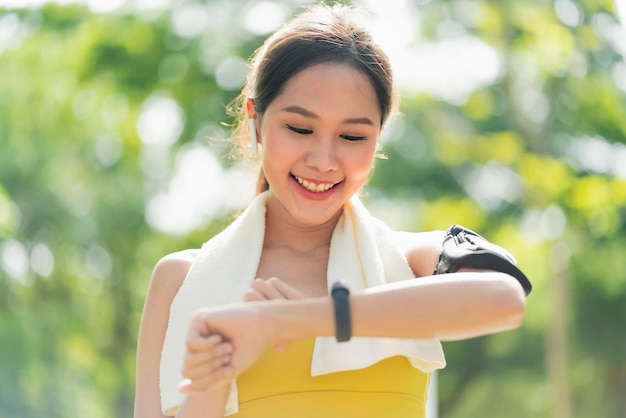 Une femme asiatique de remise en forme configure une montre intelligente avant de courir l'entraînement pendant l'entraînement du matin