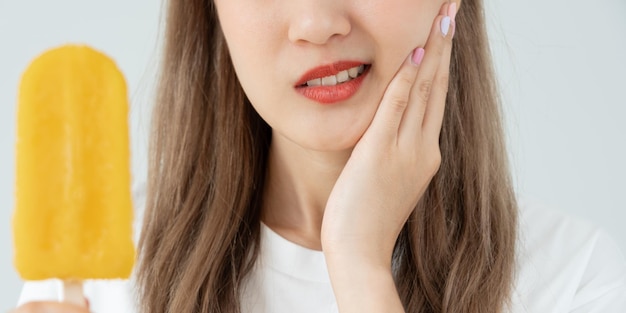 Une femme asiatique ressent des dents sensibles après avoir mangé de la crème glacée une femme souffre de problèmes de carie dentaire soins dentaires extraction dentaire problème de carie mauvaise haleine récession gingivale instruction d'hygiène buccale