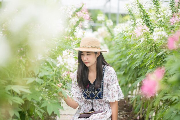 Femme asiatique avec une robe blanche se reposant sur le champ de fleurs de Margaret Aster dans le jardin