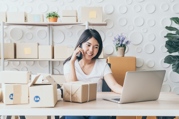 Femme asiatique s'amuser tout en utilisant internet sur ordinateur portable et téléphone au bureau