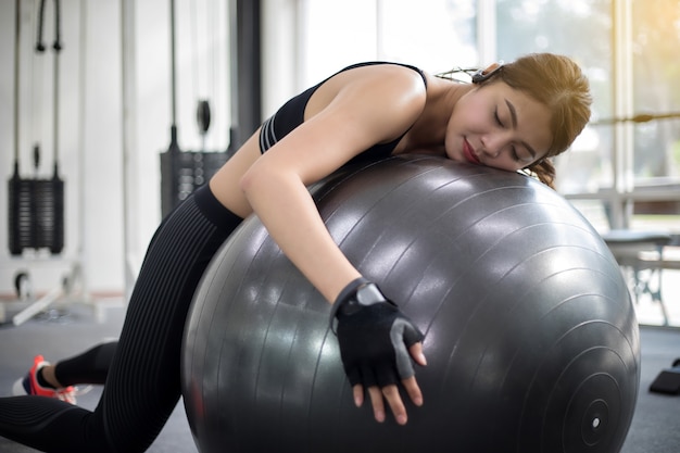 Femme asiatique s&#39;endormir après avoir fait des exercices dans la salle de gym. Fitness - concept de mode de vie sain,