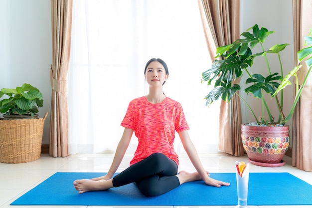 Photo une femme asiatique s'exerce dans son salon avec un tapis de yoga à la maison
