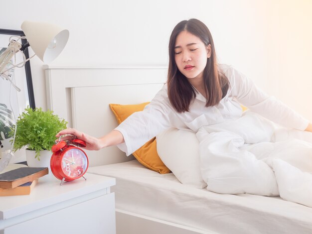 Femme asiatique se réveiller le matin et éteindre le réveil