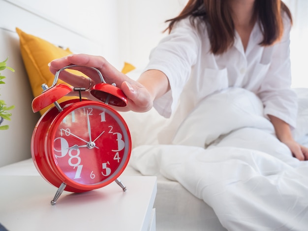 Femme asiatique se réveiller le matin et éteindre le réveil