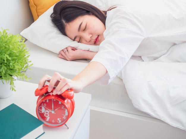 Femme asiatique se réveiller le matin et éteindre le réveil