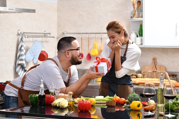 Femme asiatique se sentir heureuse lorsqu'elle est surprise par un cadeau de petit ami tout en cuisinant dans la cuisine et en préparant des aliments sains ensemble