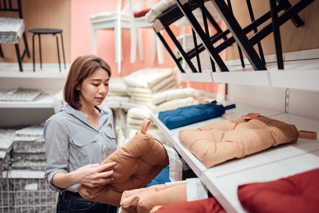 Une femme asiatique sélectionne un coussin de siège au centre commercial