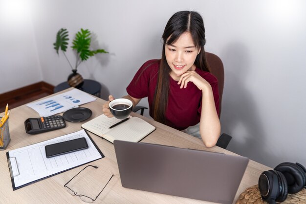 Femme asiatique songeuse se détend sur le bureau travaillant à distance de la maison