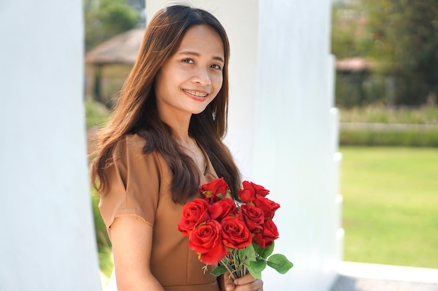 Femme asiatique souriant joyeusement parmi de belles fleurs