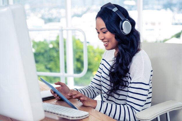 Femme asiatique souriante avec un casque avec tablette au bureau