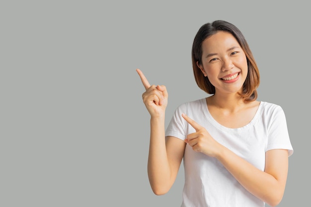 femme asiatique sourire et main pointant isolé sur fond gris