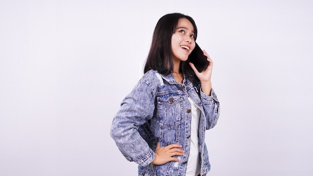 Femme asiatique, sourire, porter, veste jeans, et, parler téléphone mobile, à, isolé, blanc, surface