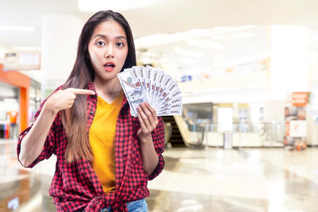 Femme asiatique tenant de l'argent dans le centre commercial