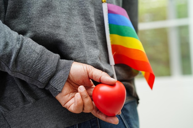 Femme asiatique tenant un hert rouge avec drapeau arc-en-ciel Symbole LGBT droits et égalité des sexes Mois de la fierté LGBT en juin