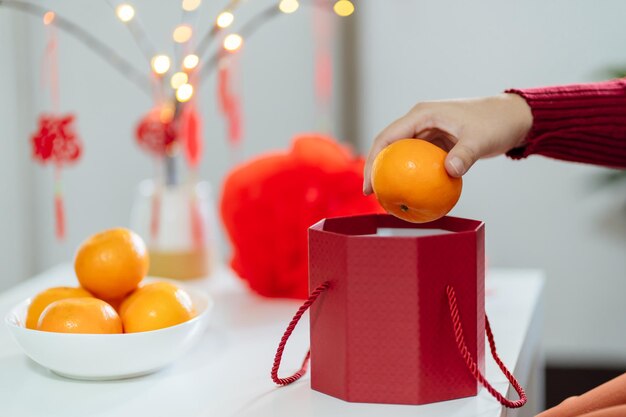 Femme asiatique tenant des mandarines avec une boîte cadeau rouge reconnaissante présente le Nouvel An lunaire chinois