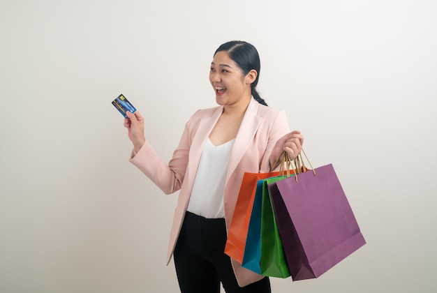 Femme asiatique tenant un sac à provisions et une carte de crédit à portée de main avec un fond blanc