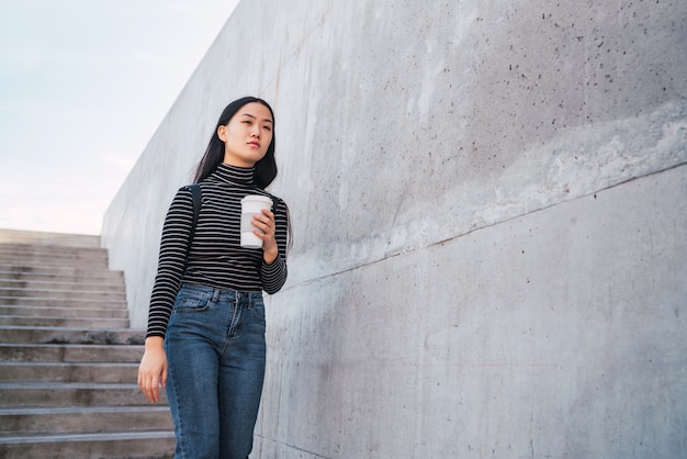 Femme asiatique tenant une tasse de café.