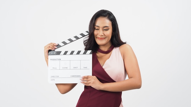 Une femme asiatique tient un panneau de battant ou une ardoise de film dans la production vidéo, le cinéma, le cinéma, l'industrie du cinéma sur fond blanc.