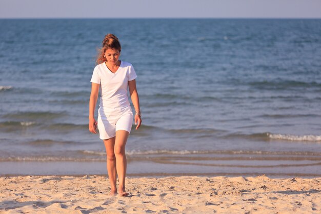 Femme asiatique en tissu blanc marchant sur la plage tropicale