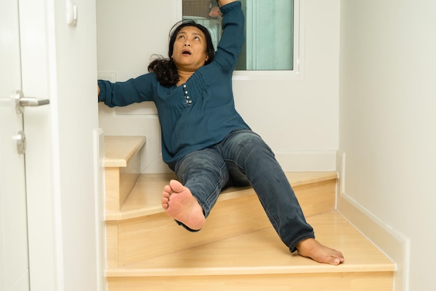 Une femme asiatique tombe dans les escaliers et a mal à la hanche et à la taille à cause de surfaces glissantes.