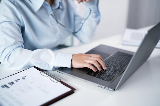 Femme asiatique travaillant à l'aide d'un ordinateur portable, tapant à la main sur le clavier, travaillant au bureau, investisseur professionnel travaillant sur un nouveau projet de start-up.