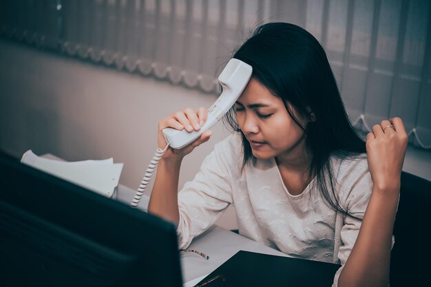 Femme asiatique travaillant au bureaujeune femme d'affaires stressée par la surcharge de travail avec beaucoup de fichiers sur le bureau