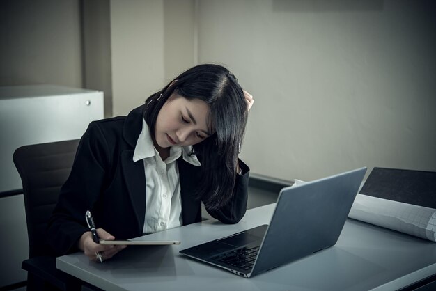 Femme asiatique travaillant au bureaujeune femme d'affaires stressée par la surcharge de travail avec beaucoup de fichiers sur le bureau