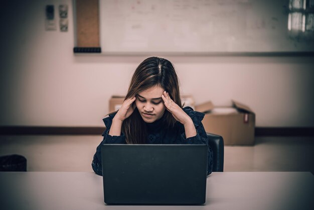 Femme asiatique travaillant au bureaujeune femme d'affaires stressée par la surcharge de travail avec beaucoup de fichiers sur le bureau