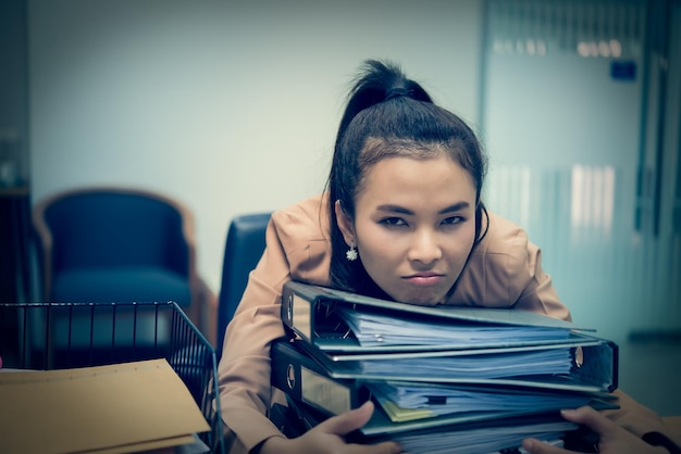 Femme asiatique travaillant au bureaujeune femme d'affaires stressée par la surcharge de travail avec beaucoup de fichiers sur le bureau