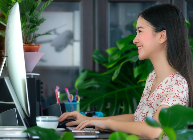 Photo femme asiatique travaillant sur le bureau de l'ordinateur dans son bureau à la maison et travaillant