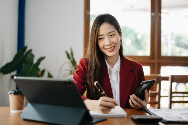 Femme asiatique travaillant dans un bureau avec des documents de travail sur une tablette et un ordinateur portable