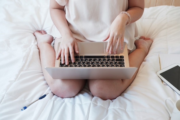 Femme asiatique travaillant ou faisant du shopping en ligne avec un ordinateur portable dans la chambre.