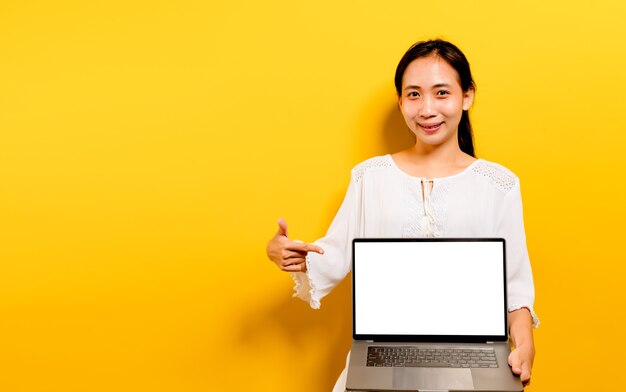 Femme asiatique travaillant sur son ordinateur portable et un sourire heureux concept de travail heureux sur fond jaune dans le studio