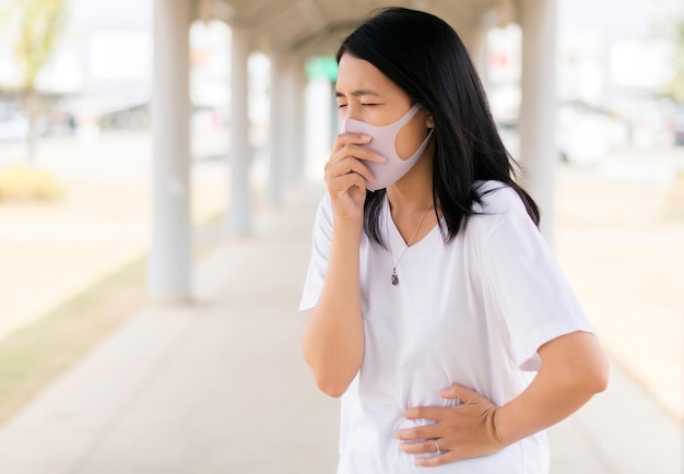 Une femme asiatique utilisant un masque protège PM 25 parce que la pollution en plein air a une allergie au nez