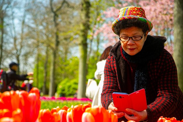 Femme asiatique utilisant un smartphone pour prendre des fleurs de tulipes photo en Natherland